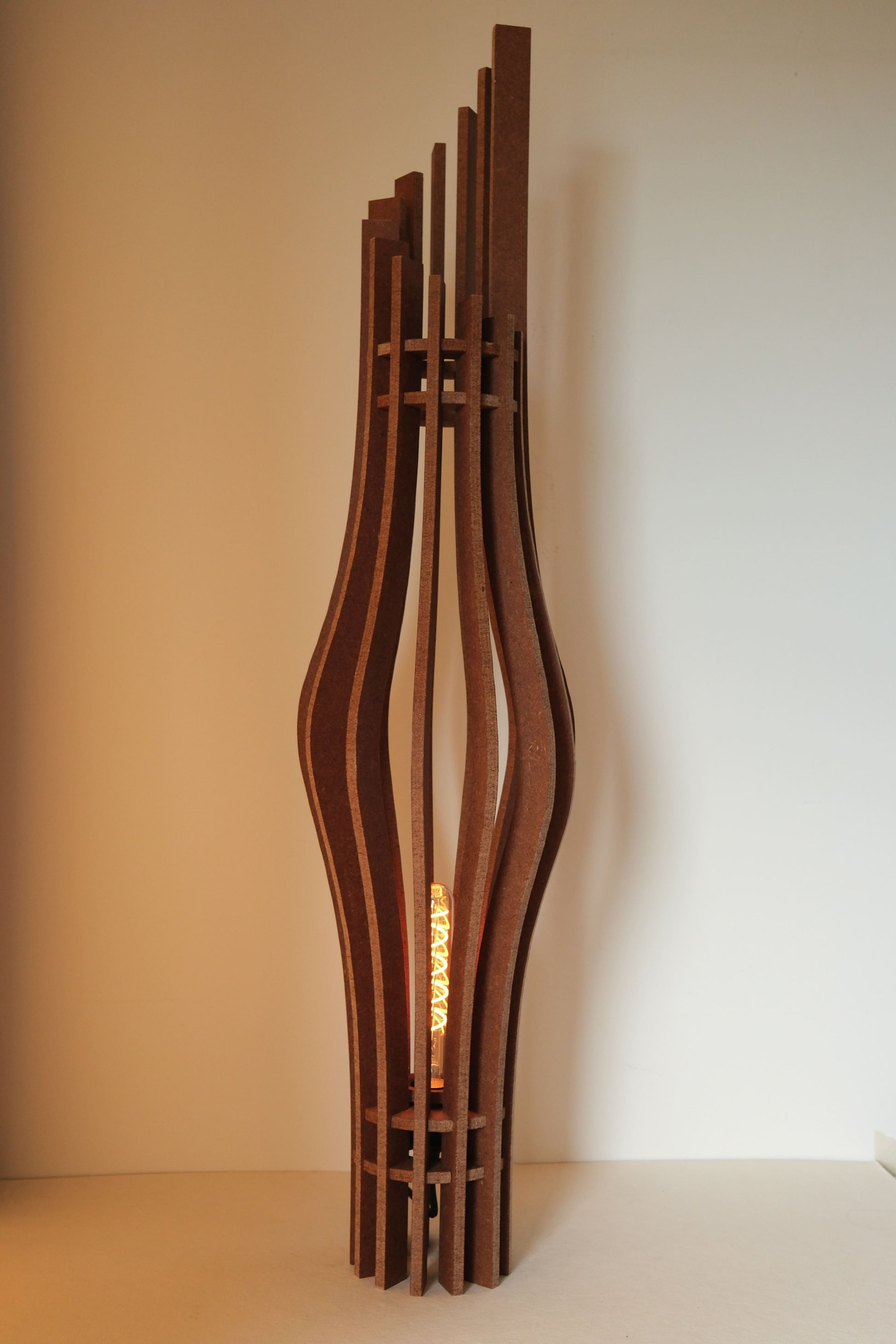De Zaangolf design vloerlamp van 9 mm MDF in Amber afwerking, golvende vorm in warm licht
