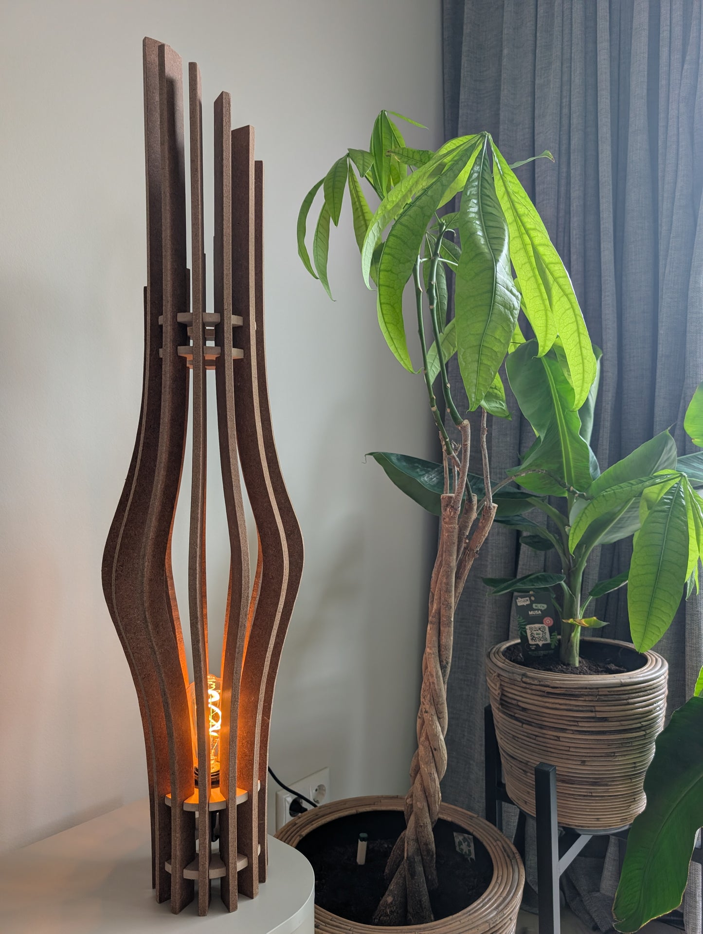 De Zaangolf handgemaakte houten design vloerlamp in Amber afwerking, 98 cm hoog, naast een zithoek