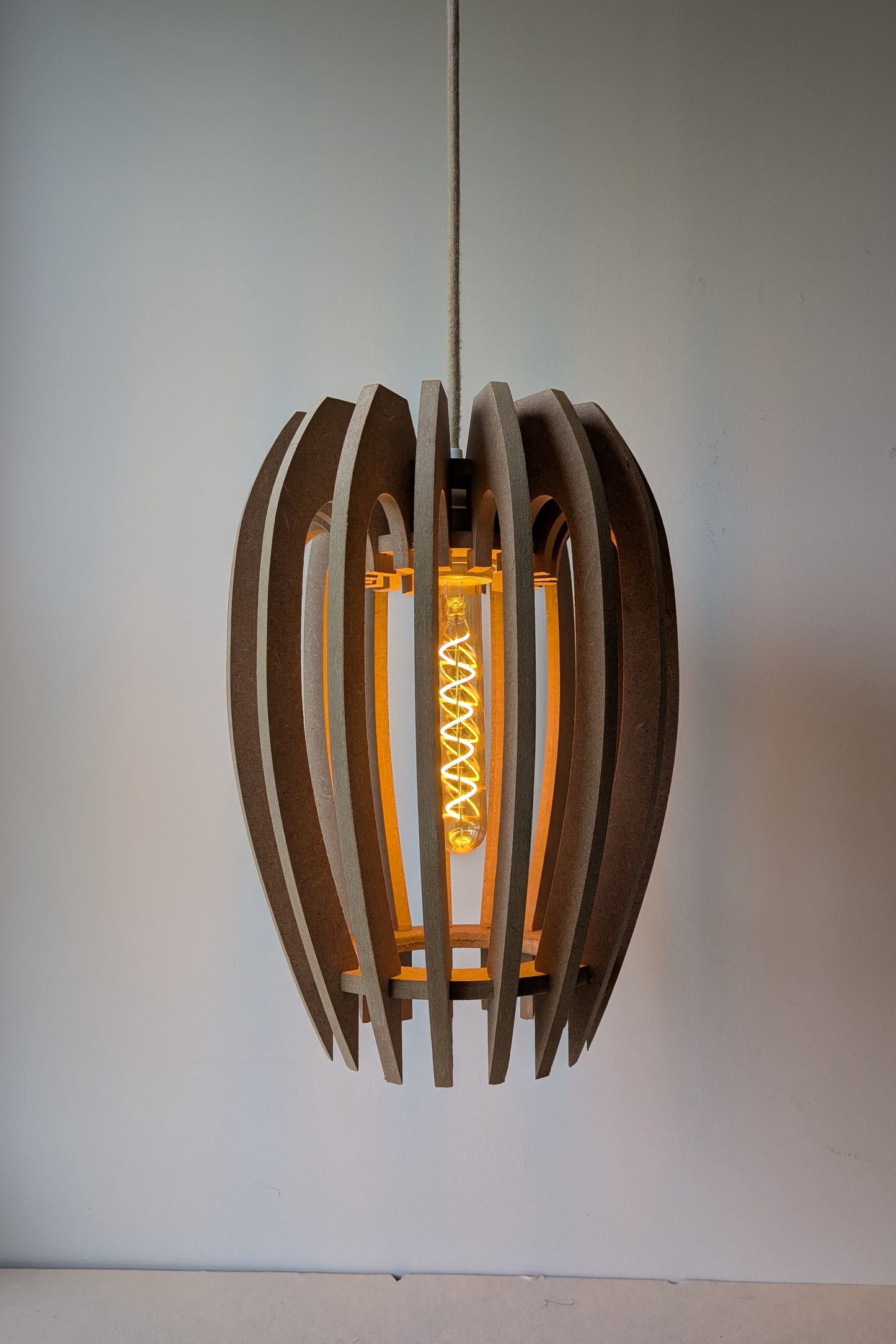 De Mantel design hanglamp van MDF in Naturel afwerking met dimbare lamp aan, warme sfeerverlichting