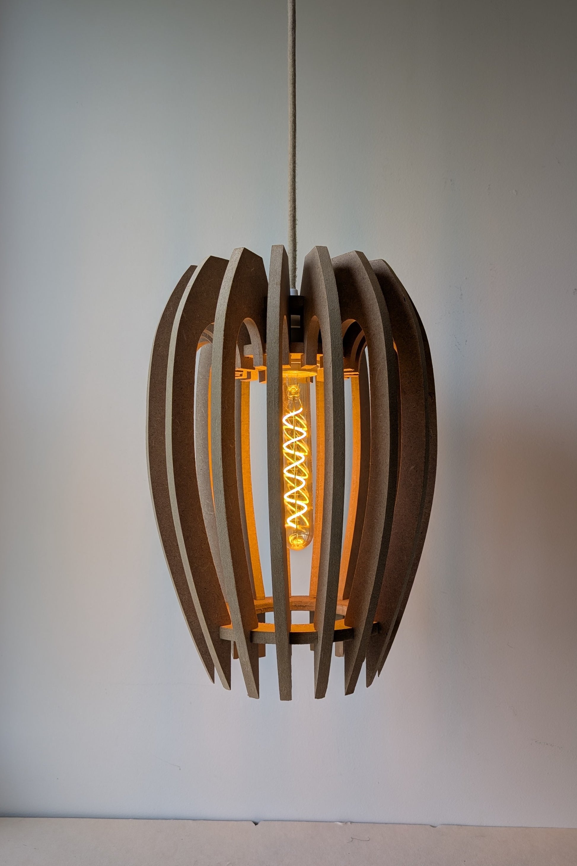De Mantel design hanglamp van MDF in Naturel afwerking met dimbare lamp aan, warme sfeerverlichting