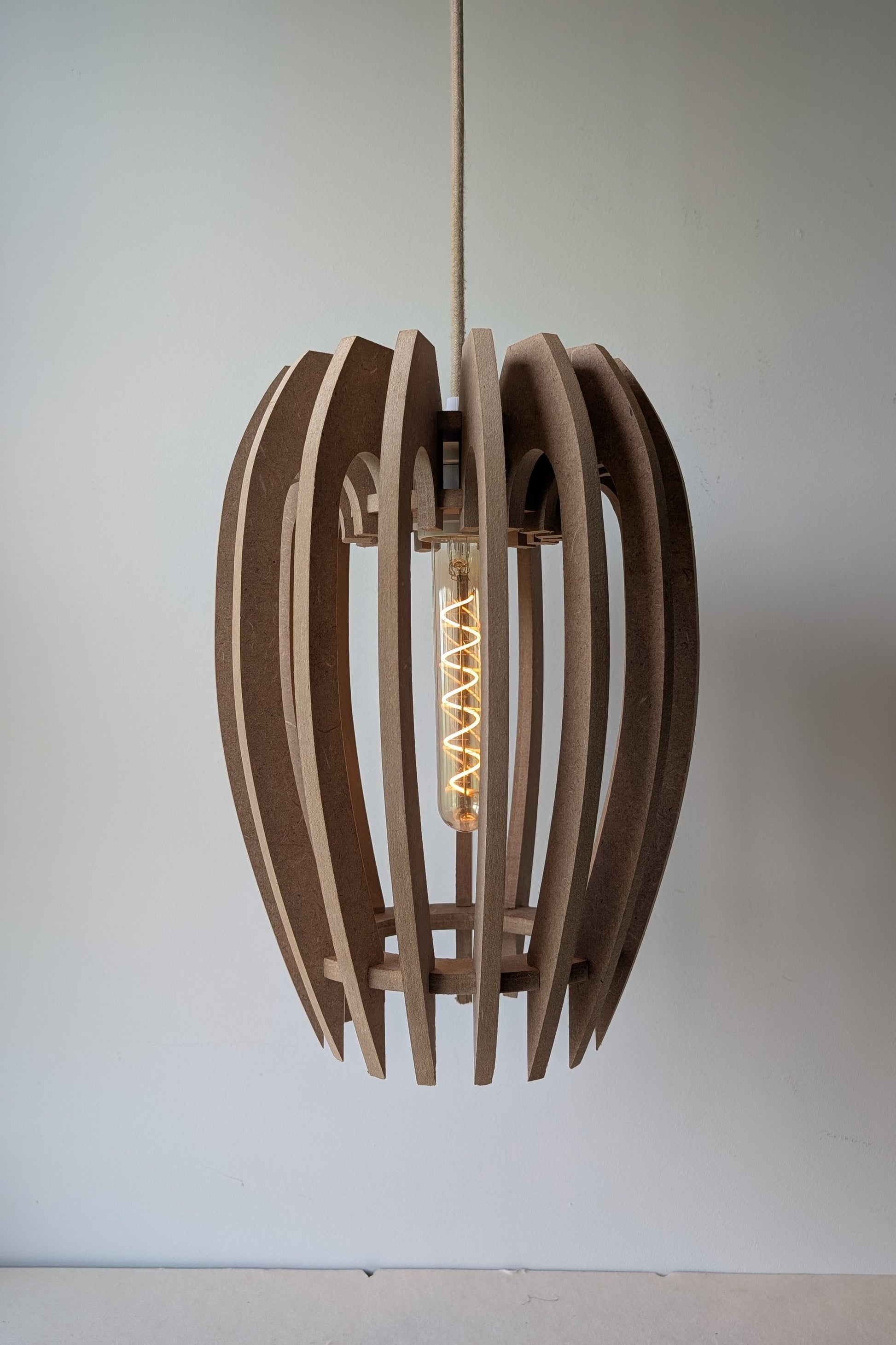 De Mantel design hanglamp van MDF in Naturel afwerking met dimbare lamp aan, warme sfeerverlichting